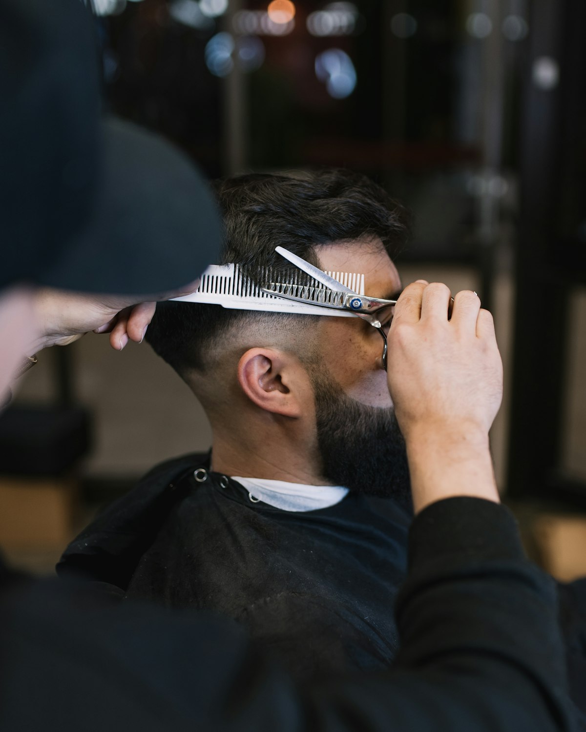 Barber giving a precision haircut with scissors and comb